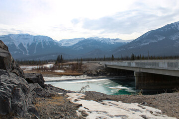 Icy river flowing under bridge surrounded by rocks in the mountains