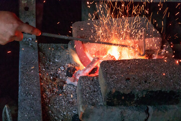 Europe, Romania. Viscri. Local Gypsy blacksmith. Firing the horse shoe in the flames.