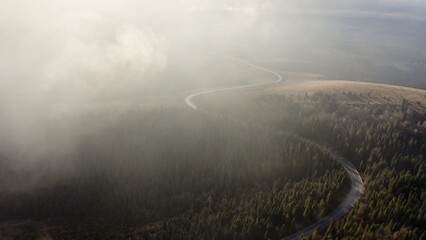 Veiled in Mist: Aerial View of a Road Through Forested Hills