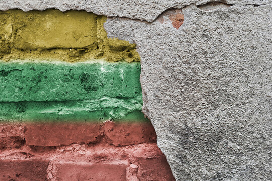 Lithuania flag on a brick wall. Yellow, green, red stripes on a stone texture. State colors of the Republic of Lithuania. Day of Restoration of Independence.