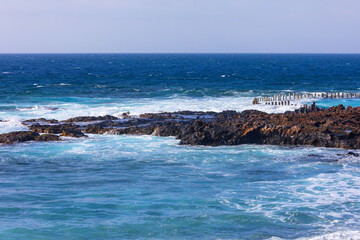 Rocks are scattered along the ocean shoreline.  Atlantic Ocean waves crash against the rocky shoreline of the Canary Islands