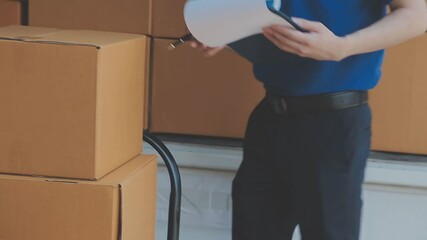 Young cheerful delivery man with parcel near car full of cardboard boxes, full length shot. Shipping service concept