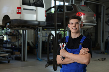 Young auto mechanic with wrenches at automobile repair shop
