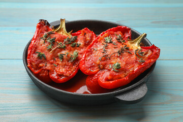 Tasty stuffed peppers in dish on light blue wooden table
