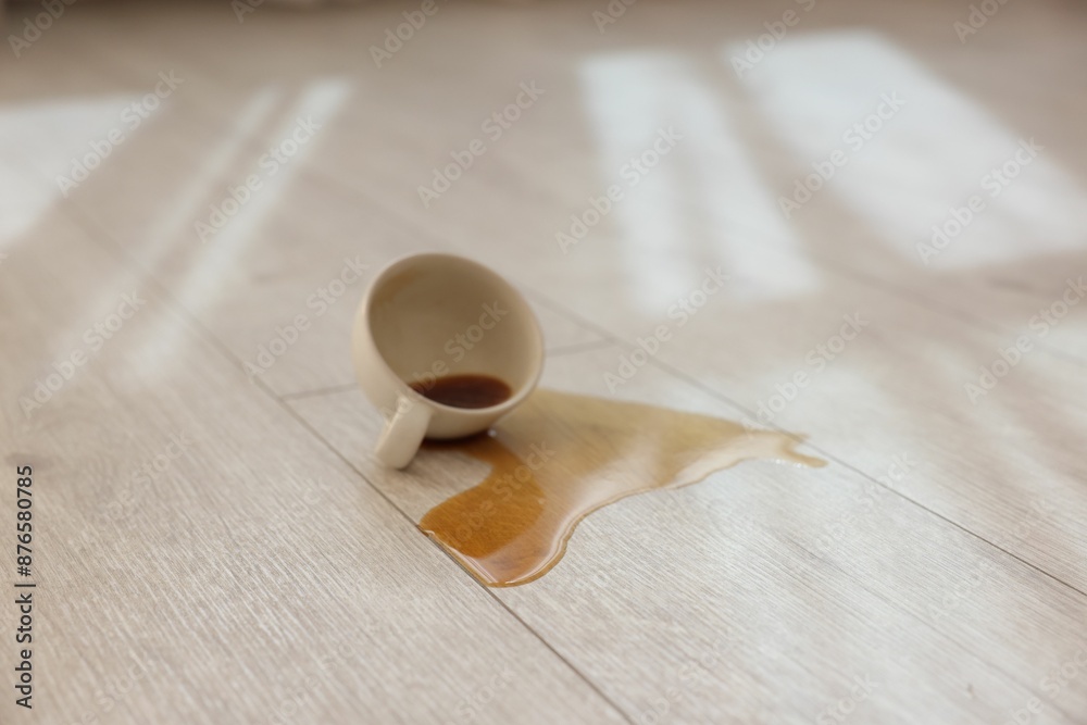 Wall mural Cup with spilled drink on wooden floor