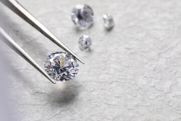 Tweezers with beautiful shiny diamonds on light textured background, closeup. Space for text
