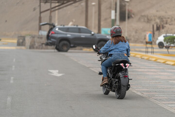 Fototapeta premium Latin woman driving a motorbike on a road