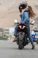 Woman taking off her helmet sitting on a motorbike