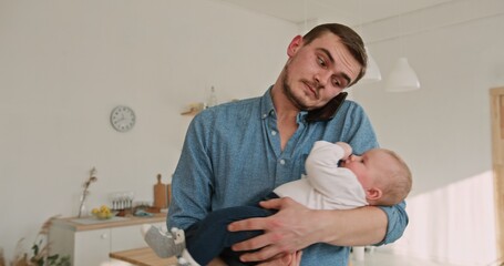 Obraz premium Multitasking Dad Balancing Work Call with Holding Adorable Son at Home