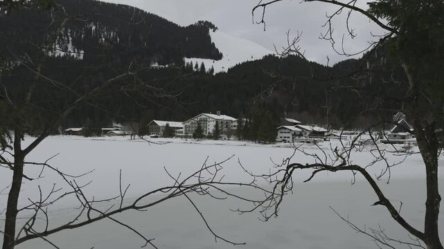 Lake Spitzingsee in winter covered with snow and ice in freezing cloudy weather in Bavaria, Germany. A mountain lake in Bavarian Alps frozen around mountain in Spitzingsee, Schlierseer Berge 