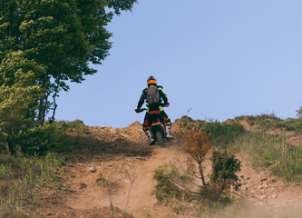 Professional enduro bike rider on action, dirt ride on the muddy road. Motocross sport. 
