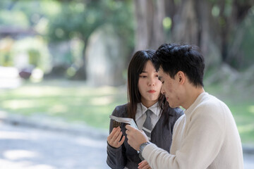 In March, a Taiwanese woman in her twenties and a Hong Kong man are taking a break in a park in Zhongzheng District, Taipei City, Taiwan, eating snacks and drinking water.