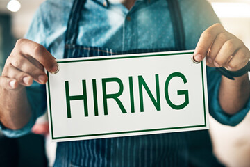 Hands, hiring and work sign at small business with employee search, recruitment and cafe vacancy. Coffee shop, person and board with job employment request for store help and admin for entrepreneur