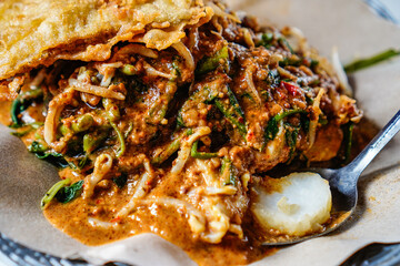 pecel dish consisting of mixed vegetables with peanut sauce and served with lontong rice, a typical Indonesian food concept.