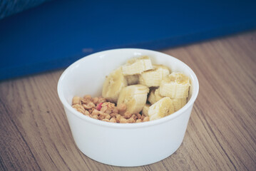 Asian women eating cereal oatmeal with milk organic nutrition ingredients. Women hands holding spoon and bowl with healthy dairy product cereal, fruits, banana. Dietary healthy lifestyle at home