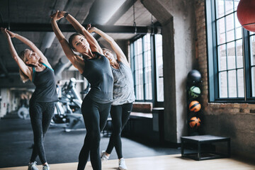 Women, people and stretching with fitness, exercise and balance with workout, active and performance. Healthy group, athlete or friends in wellness center, routine and cardio with warm up or training