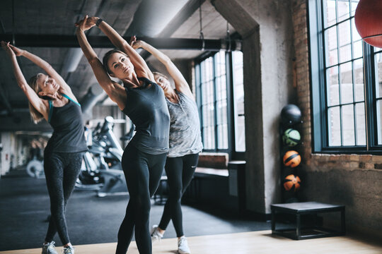Women, people and stretching with fitness, exercise and balance with workout, active and performance. Healthy group, athlete or friends in wellness center, routine and cardio with warm up or training