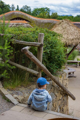 A little toddler in jeans has fun watching the animals at a modern urban zoo