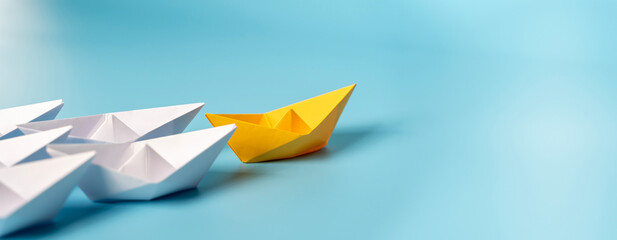 Paper boat leads the fleet with new ones joining the team. Teamwork, cooperation.