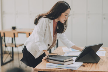 Happy young asian businesswoman sitting on her workplace in the office. Young woman working at laptop in the office.