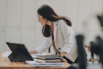 Happy young asian businesswoman sitting on her workplace in the office. Young woman working at laptop in the office.