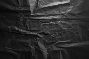 Dramatic black crumpled paper texture in low light background