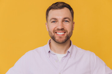 Fototapeta premium Cute smiling unshaven man in purple shirt posing isolated on yellow background