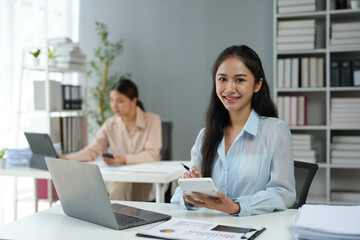 Asian businesswoman works on laptop and calculates with financial calculator from graphs, statistics, charts. Planning. Business success results in modern office.