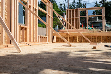 Wood framing started on new home construction job site, exterior walls with windows and subfloor
