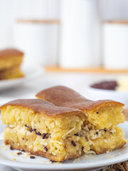 Close-up of a plate with Martabak Manis, an Indonesian sweet pancake filled with cheese and chocolate. Another plate with Martabak is visible in the blurred background.