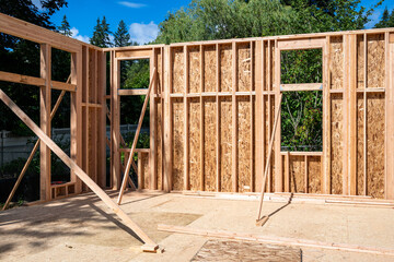 Wood framing started on new home construction job site, exterior walls with windows and subfloor
