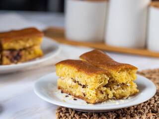 Close-up of a plate with Martabak Manis, an Indonesian sweet pancake filled with cheese and chocolate. Another plate with Martabak is visible in the blurred background.