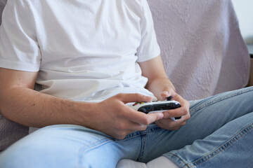 Close-up of a young man playing video games on a console.