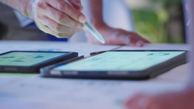 close up diversity team brainstorming focused on ESG (environment,social,governance) carbon footprint with tablet or sdgs goals in a sustainable green office at night