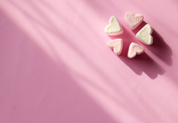 Marshmallow hearts on a pink background with copy space. Romantic pink background. Valentine's Day symbols tender marshmallow sweets heart shape.