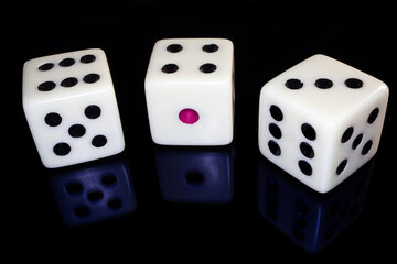Three white dices isolated on black reflective background