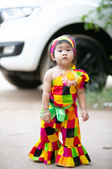 A portrait of a young Asian girl wearing a colorful dress and a festive hat, smiling happily cute little asian 

