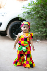 A portrait of a young Asian girl wearing a colorful dress and a festive hat, smiling happily cute little asian 

