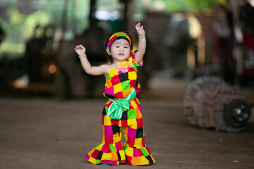 A portrait of a young Asian girl wearing a colorful dress and a festive hat, smiling happily cute little asian 

