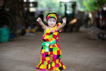A portrait of a young Asian girl wearing a colorful dress and a festive hat, smiling happily cute little asian 

