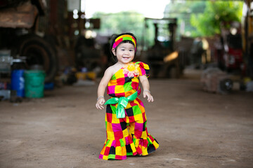 A portrait of a young Asian girl wearing a colorful dress and a festive hat, smiling happily cute little asian 

