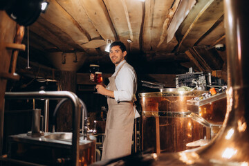 Brewery worker looking at freshly made beer in glass mug