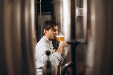 brewer checking beer for qaulity at brewery while holding clipboard