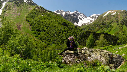 Girl enjoying view from large rock in mountainous region.