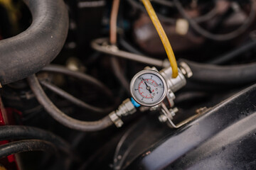 Fototapeta premium limbazi, Latvia, June 29, 2024 - Close-up of a car engine's pressure gauge with hoses and wiring visible, showcasing mechanical details and functionality. Some copy space...