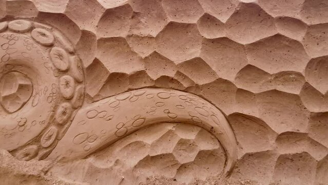 A bas-relief created from sand with an octopus.