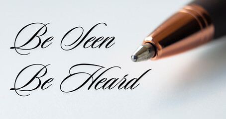 Fototapeta premium Be seen be heard text with closeup pen on white cover background