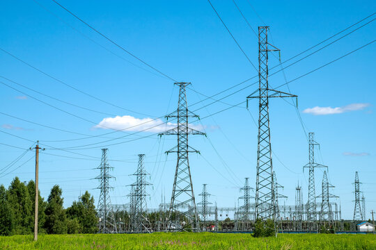 Power lines in a green field in the sunny summer day. Electrical substation. - Powered by Adobe