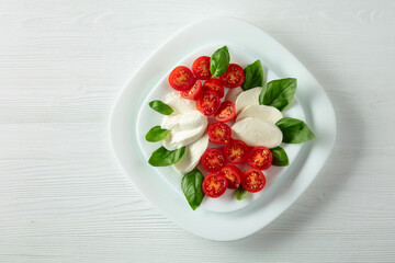 Mozzarella with basil and cherry tomatoes on a wooden table.