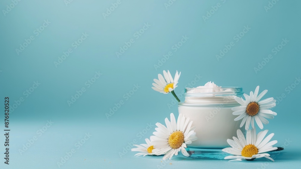 Poster Gentle baby lotion with chamomile in small jar on blue backdrop with copy space